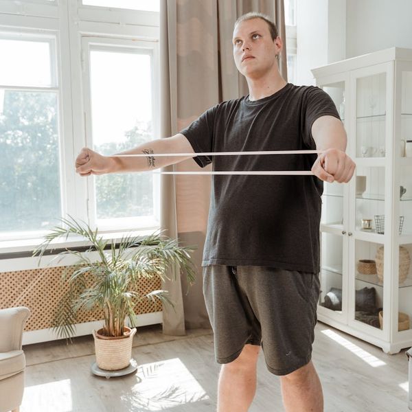 A man in athletic wear stretching indoors with natural light.